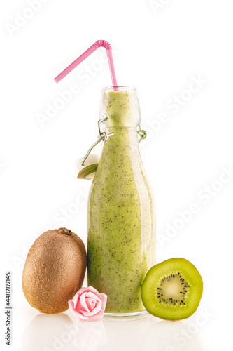Bottle of delicious green kiwi smoothie with kiwi slices and a little flower isolated on white background. Healthy, detox and diet food concept