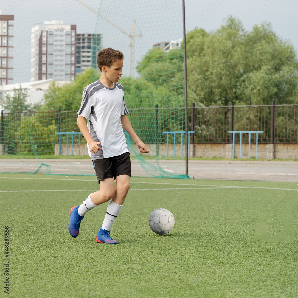 The boy loves to play football, trains with the ball on the artificial turf and scores a goal. The boy plays football The boy loves to play football, trains with the ball on the artificial turf and scores a goal. The boy plays football