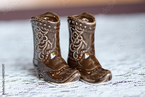 Miniature glass brown cowboy boots figurines on white lace surface