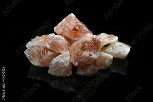 Pink himalayan crystal salt rocks on isolated black background.