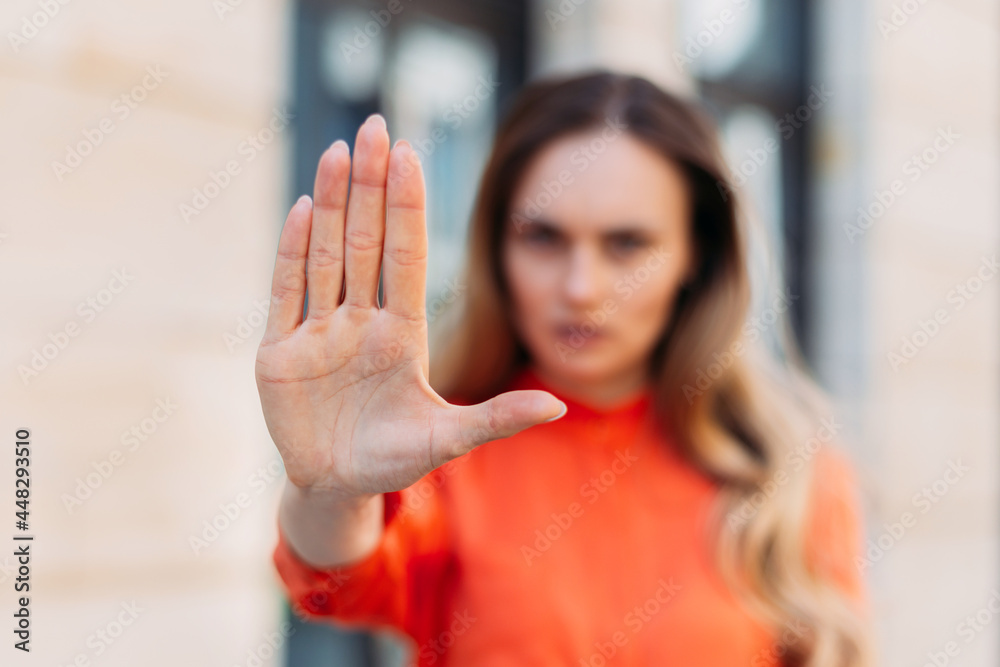 Caucasian girl with serious face with hand makes stop gesture.