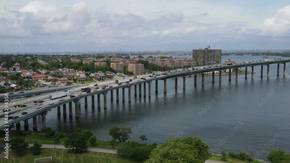 An amazing time lapse view of a highway connecting to a bridge over a body of water with a rush of cars in the shot, and buildings in the background An amazing time lapse view of a highway connecting to a bridge over a body of water with a rush of cars in the shot, and buildings in the background