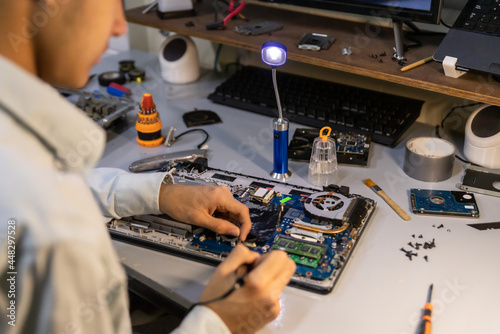 technician soldering a broken computer board