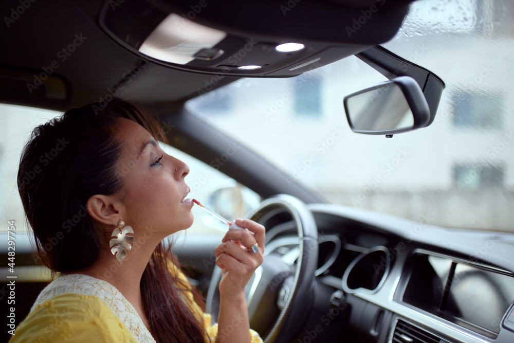 Latin woman in yellow dress painting her lips inside a car. Latin woman in yellow dress painting her lips inside a car.