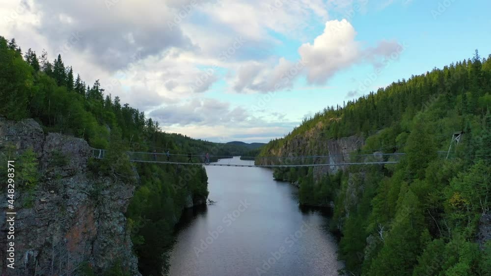 drone shot of 4 persons crossing a suspended bridge in Aiguebelle National Park, Quebec, Canada drone shot of 4 persons crossing a suspended bridge in Aiguebelle National Park, Quebec, Canada