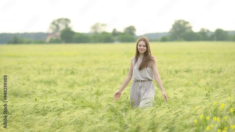Portrait of a young beautiful woman in dress walks through a wheat field at a sunny day. Happy free girl run in park agricultural land. Freedom concept. Portrait of a young beautiful woman in dress walks through a wheat field at a sunny day. Happy free girl run in park agricultural land. Freedom concept.
