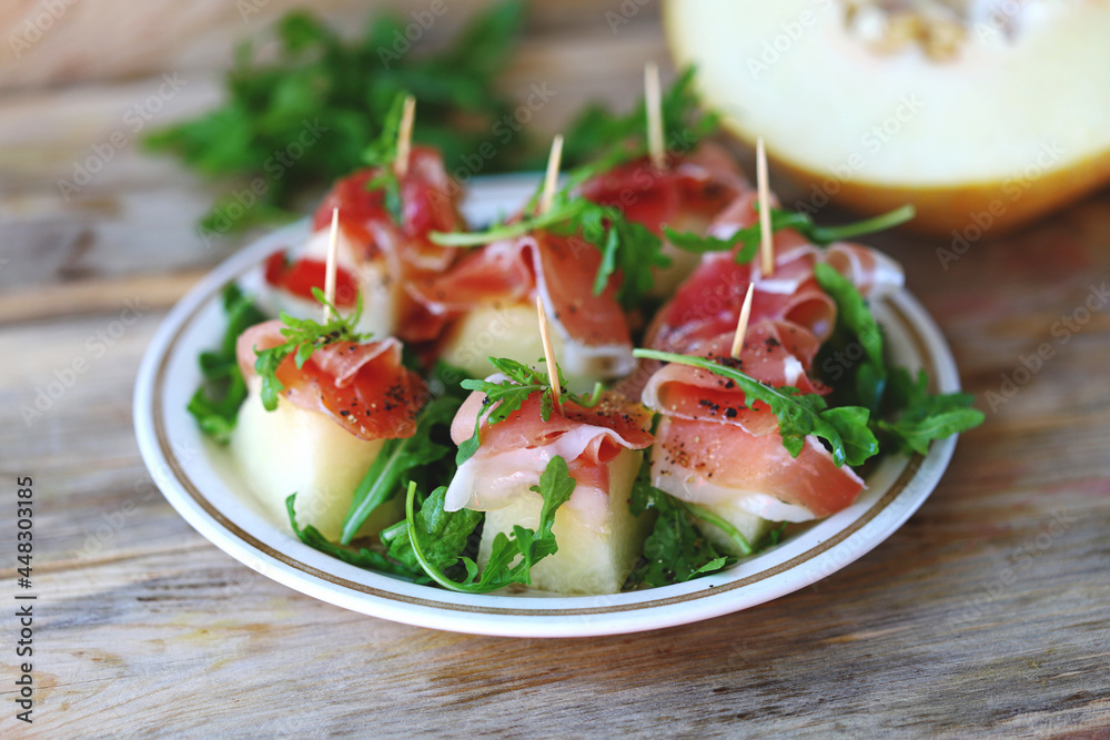 Melon jamon appetizer on a plate. Melon prosciutto salad on skewers. Melon jamon appetizer on a plate. Melon prosciutto salad on skewers.