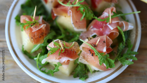Melon jamon appetizer on a plate. Melon prosciutto salad on skewers.