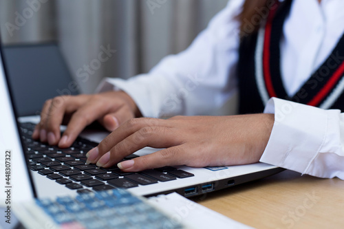 Young woman sitting  using laptop  tablet  notebook and calculator working from home. Closeup shot of unrecognizable woman  hands working on computer keyboard. 