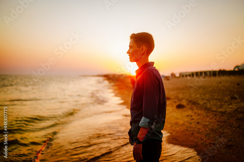 A woman of androgynous appearance looks at the sea at sunset photo