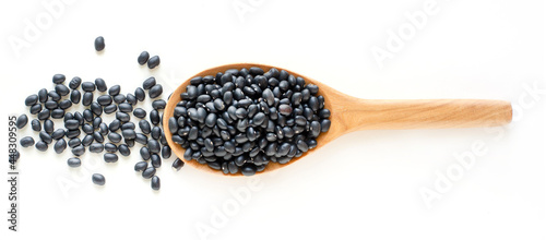 Top view of dry organic black bean seed pile in wooden spoon on white background, ready for healthy food ingredient or carbohydrate food type concept