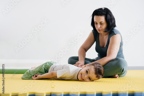 Rehabilitation of children with cerebral palsy. Physical activities for disabled kids in center. Mother, therapist doing exercise with boy on mat. Learning to move and communicate. Inclusion. 