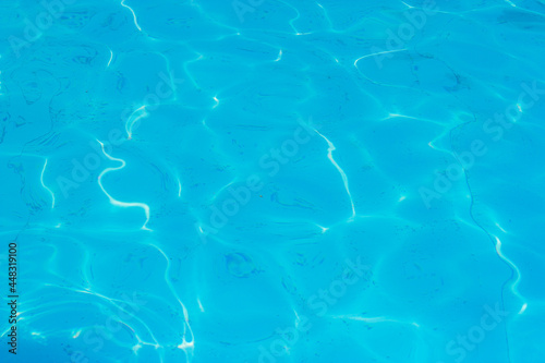 Beautiful blue ripple water surface in swimming pool with sun reflection