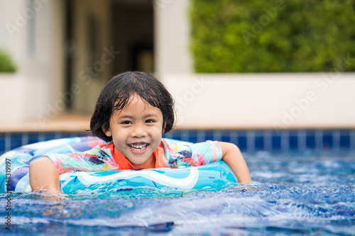 Photography Cheerful Asian female kid in a ring floater on swimming pool