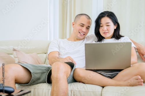 Happy young couple using a laptop together at home