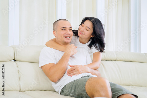 Young woman embrace her husband on the couch