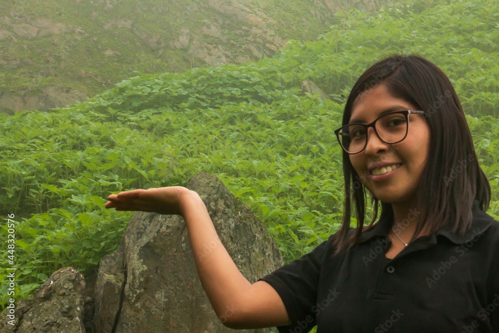 Naklejka premium Woman with outstretched hand in the middle of a cloudy landscape and a large rock.