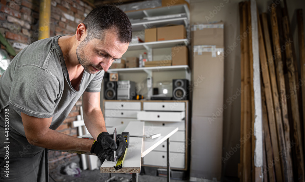 Carpenter holding a measuring tape on the work table.