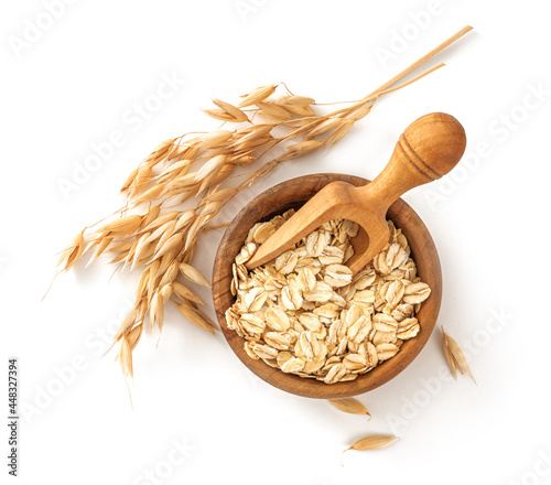 Oat flake in wooden bowl with spoon and spikelets of oats isolated. Bowl of oats on white background. Top view of oat.