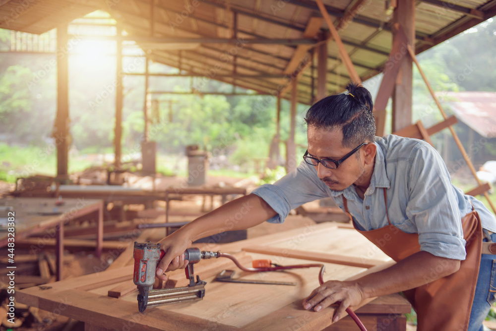 Closeup of a man carpenter using a nail gun.Carpenter using air nail gun doing wooden furniture work