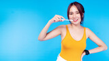 Smile young woman holding toothbrush with toothpaste while looking at camera over isolated blue background. Good oral and dental health concept.