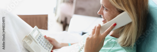 Smiling woman talking on phone while lying in of hotel room photo