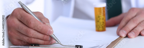Male doctor hand write prescription at office worktable