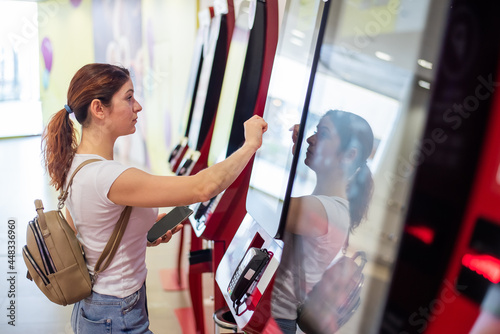 Photos Caucasian woman buying cinema ticket at self-service box office.