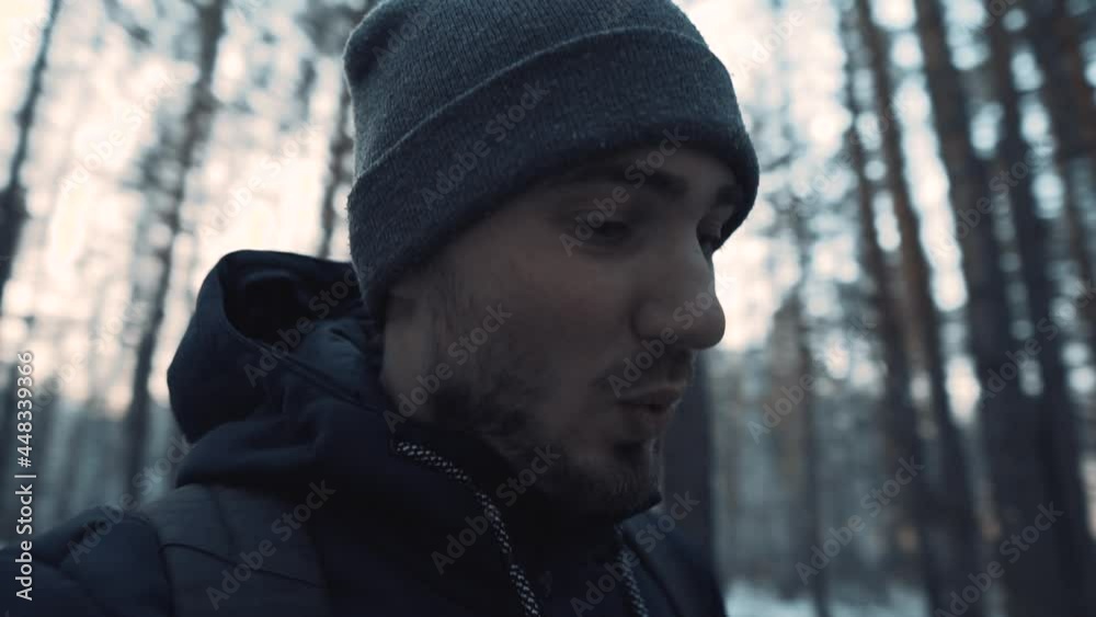 The video blogger walks and speaks to the camera against the background of a winter forest. A bearded man in a hat The video blogger walks and speaks to the camera against the background of a winter forest. A bearded man in a hat