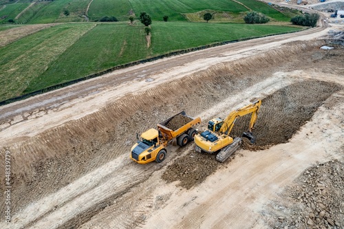 Aerial view of an excavator and truck working on a construction.