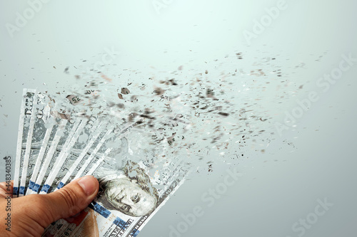Hundred dollar bills fly to dust in a man's hand. Loss of money, big expenses, loans, mortgages.