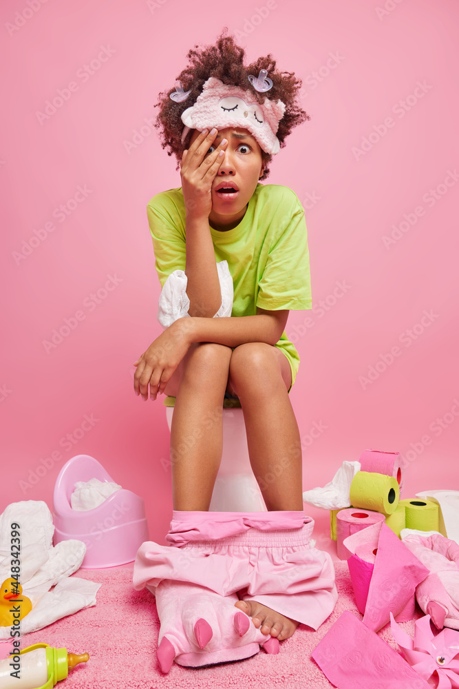 Frightened Afro American woman wears sleepmask green t shirt and shorts ...