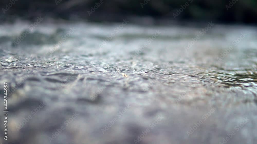 Rippling water in a lively small Swedish forest river in the summertime. Close up depth of field. Handheld realtime footage. 