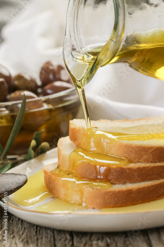 Woman pouring extra virgin olive oil on bread. Homemade helathy snack. photo