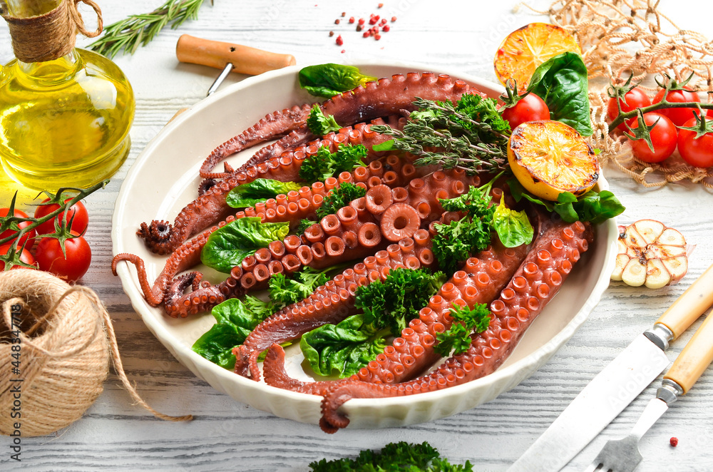 Baked octopus with spinach, lemon and parsley on a baking sheet. Top view. Flat lay. Baked octopus with spinach, lemon and parsley on a baking sheet. Top view. Flat lay.