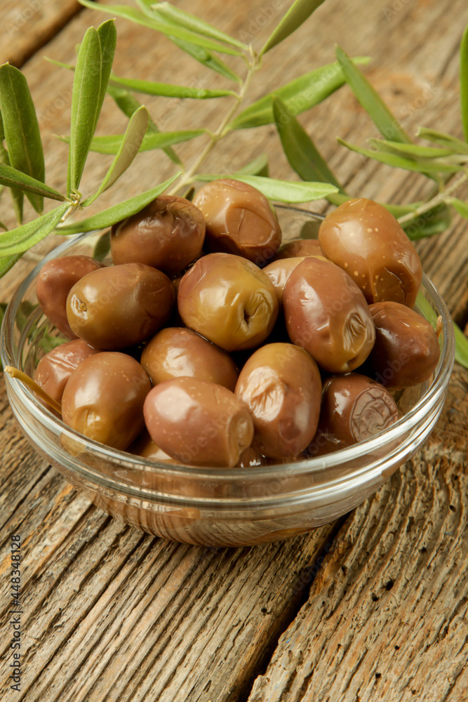 Olives and olive oil in bowl on woden table