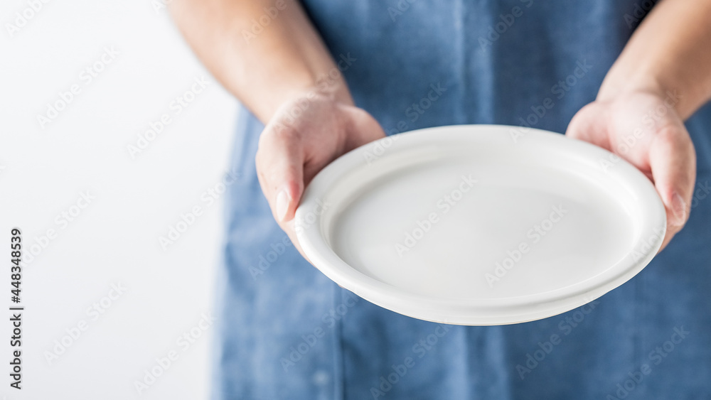 Male hands holding empty plate.
Male hands holding empty plate.