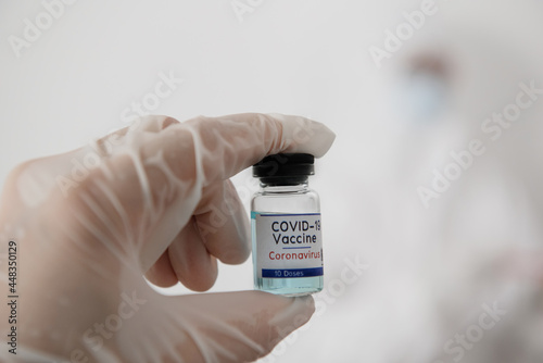 Doctor Hands in protective gloves holding Coronavirus 2019-nCoV Vaccine vial.