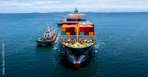 Aerial in front of cargo ship carrying container and running for export goods from cargo yard port to other ocean concept freight shipping ship .