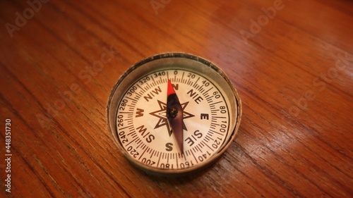 Magnetic compass indicating North closeup shot on a wooden background