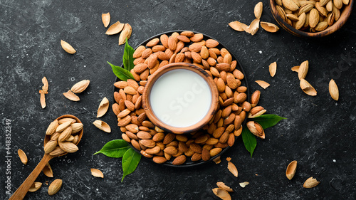 Almond milk and almonds on black stone background. Top view. Free space for your text.