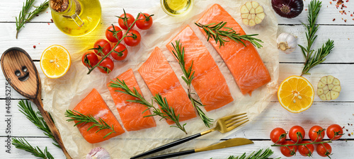 Pieces of raw salmon, vegetables, spices and herbs on a white wooden background. Recipe. Seafood. Free space for text.