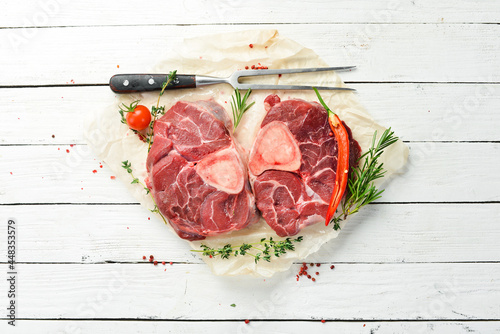 Meat. Osso buco Veal steak with rosemary and spices. On a white wooden background. Top view.