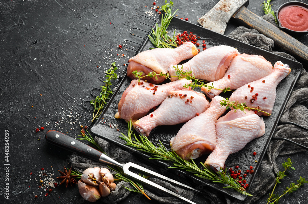 Raw chicken drumsticks with spices on a black stone background. Meat. Top view. Rustic style. Raw chicken drumsticks with spices on a black stone background. Meat. Top view. Rustic style.