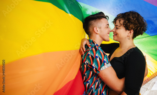 Affectionate queer lovers bonding against a rainbow flag photo