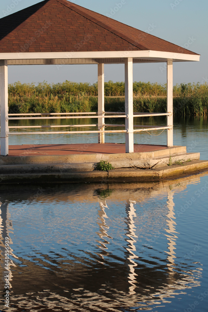 Gazebo on the lake with its reflection on the water