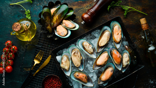 Metal tray with raw mussels. Seafood. On a black stone background. Free space for text.