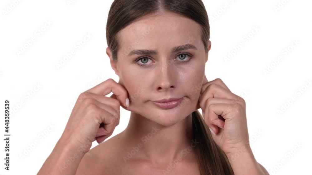 Portrait of a Caucasian woman, tugging on the skin on her face. Unsatisfied because of skin folds. White background. Portrait of a Caucasian woman, tugging on the skin on her face. Unsatisfied because of skin folds. White background.