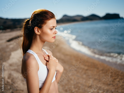 Woman in white swimsuit on the beach posing sun charm