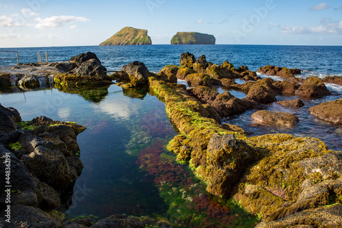 Rocky coast of the sea. Natural pools of Terceira with the Ilhéus das Cabras in the background.